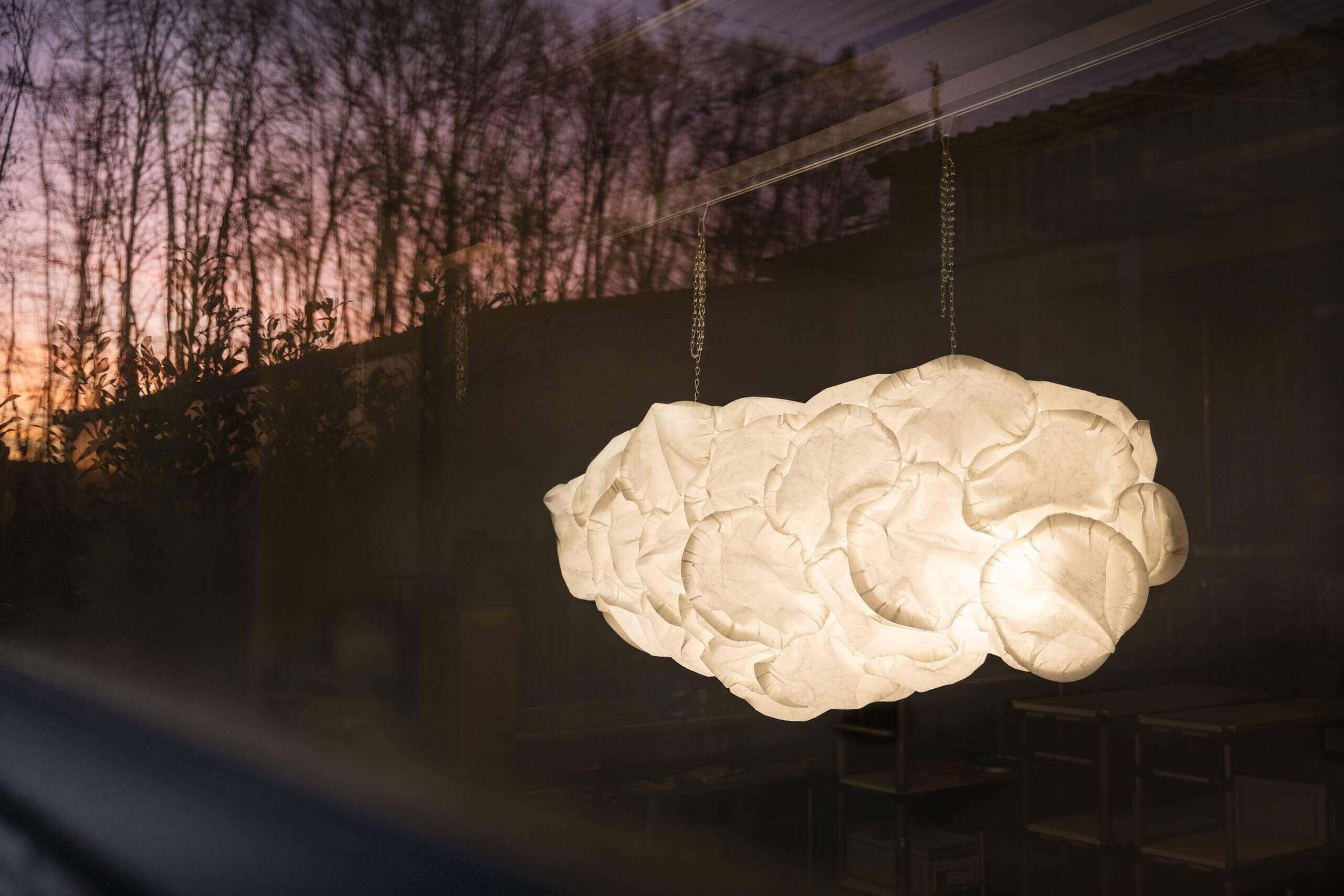 Cloud pendant lamp by Belux in warm light with sunset in the background.