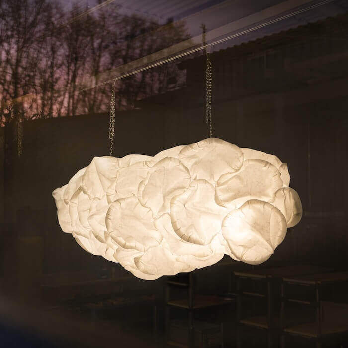 Cloud pendant lamp by Belux in warm light with sunset in the background.