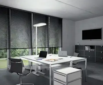 Modernes Büro mit Schreibtisch, Stühlen und Fensterblick ins Grüne.