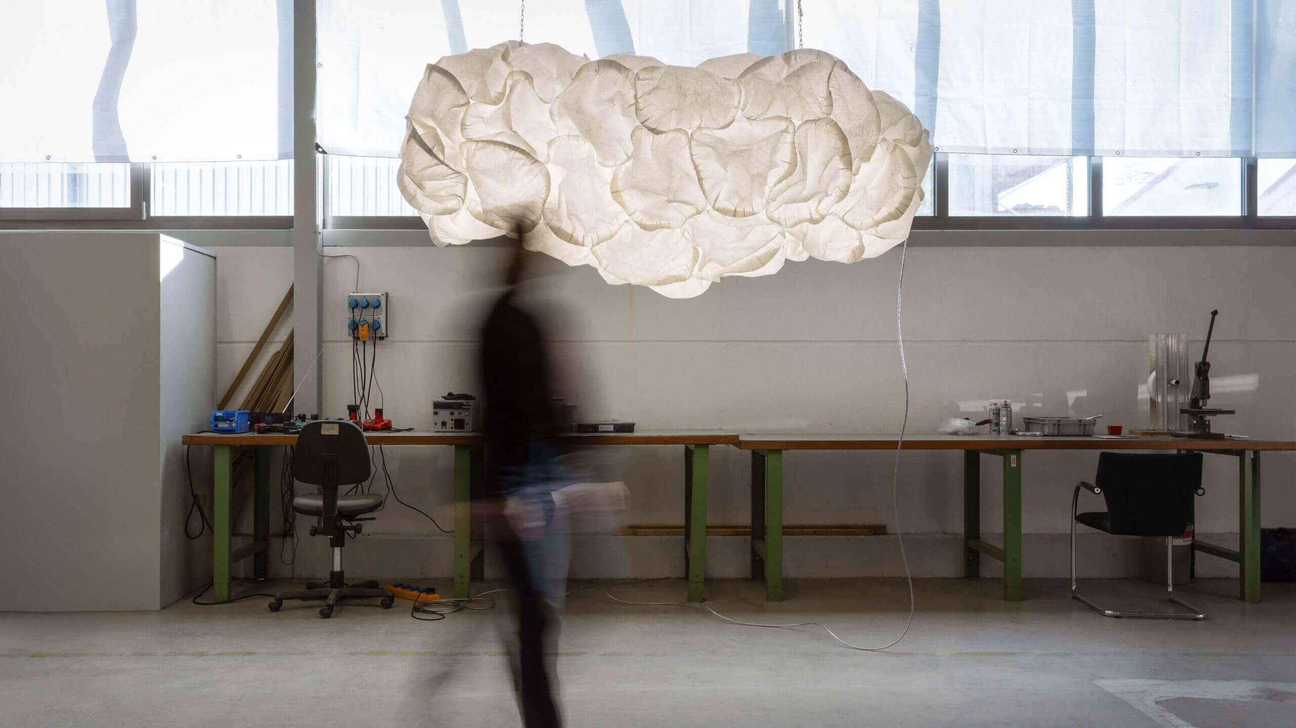 Lampenmodell Cloud von Belux schwebt in einem Atelier mit Holzarbeiten.