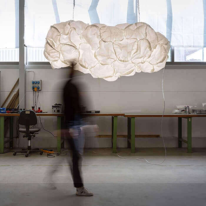 Lampenmodell Cloud von Belux schwebt in einem Atelier mit Holzarbeiten.